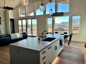 A modern kitchen with a large island, large windows, and a view of the mountains. - Luxury Modern farmhouse, Strong WiFi, Stunning Granite Mountain Views (Prescott)