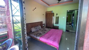 Een slaapkamer met een bed, een kledingkast, een plafondventilator en een glazen deur naar een balkon.