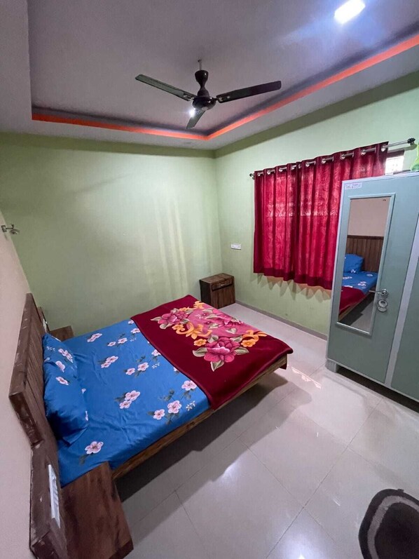 A bedroom with a bed, a wardrobe, a ceiling fan, and a window with curtains.