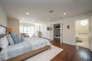 A bedroom with a bed, a nightstand, a dresser, and a window.