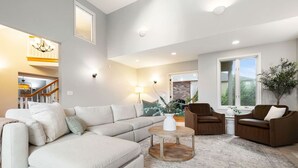 A spacious living room with a sectional sofa, two armchairs, a coffee table, and a large window providing natural light.