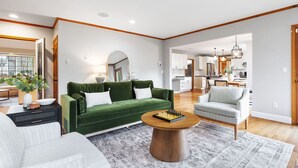 A modern living room with a green sofa, a grey armchair, and a wooden coffee table.