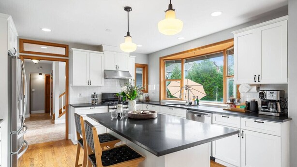 A modern kitchen with white cabinets, a large island, and pendant lighting.