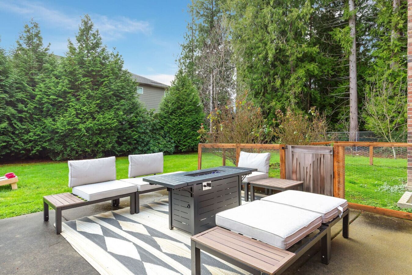 Eine Terrasse im Freien mit Esstisch, zwei Bänken und einem Grill.