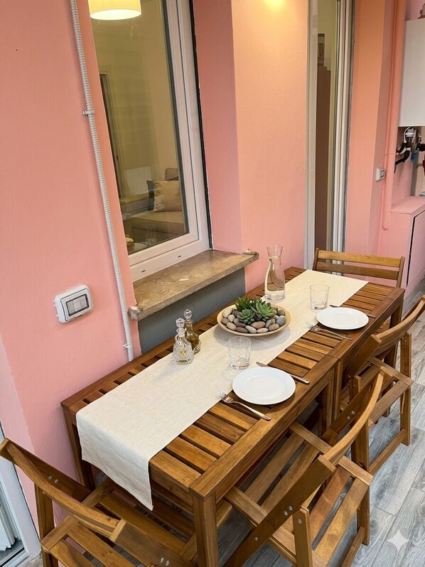 A wooden dining table set with plates, glasses, and a centerpiece of stones and a small plant.