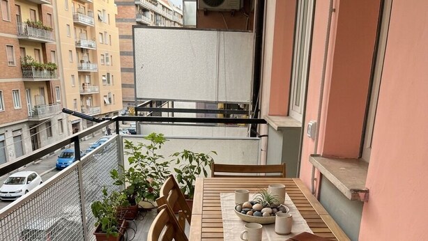 A wooden table with chairs on a balcony with a view of a cityscape.