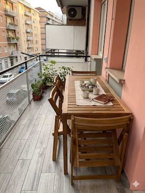 Una mesa de madera con sillas en un balcón con vista a un paisaje urbano.