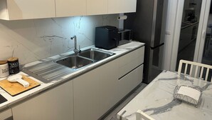 A modern kitchen with a stainless steel sink, a black coffee machine, and a refrigerator.