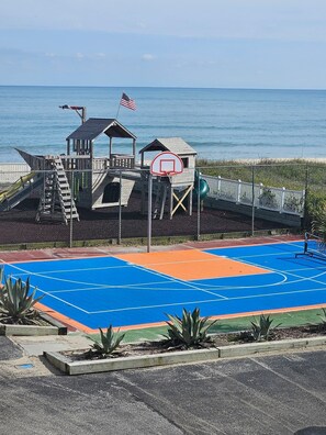 En basketballbane med en trækonstruktion, et flag og udsigt over havet.