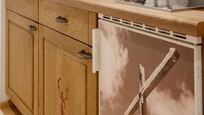 Una cocina con armarios de madera, una cafetera y una campana extractora fijada a la pared.
