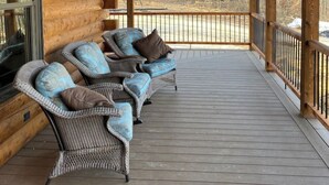 A covered porch with wicker furniture and a view of a wooded area. - Custom Log Cabin in French Lick (French Lick)