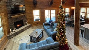 A log cabin interior with a stone fireplace, a large ceiling fan, and a Christmas tree. - Custom Log Cabin in French Lick (French Lick)