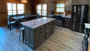 A spacious kitchen with a large island, wooden ceiling, and modern appliances. - Custom Log Cabin in French Lick (French Lick)