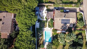 Vista aérea de una zona residencial con varias casas, una piscina e instalación de paneles solares.