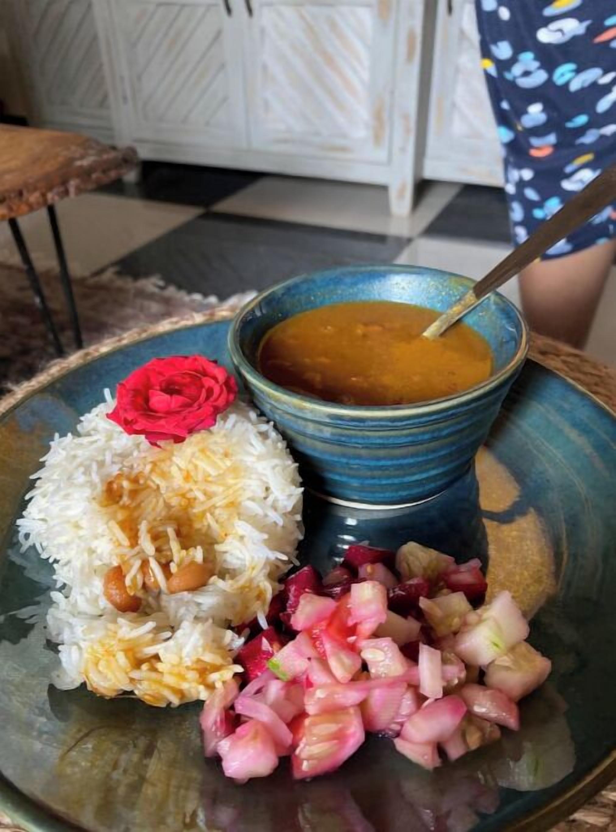 A plate with rice, beans, chopped onions, and a bowl of soup.