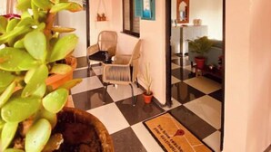 Un vestíbulo de hotel con piso a cuadros, techo de madera y una planta en maceta al frente.