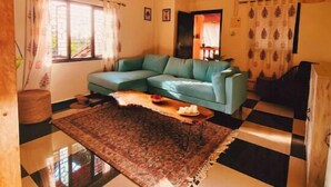 Una sala con piso a cuadros, un sofá azul y un ventilador de techo.
