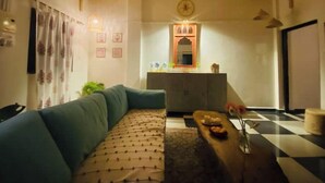 Una sala de estar con un sofá, una mesa de centro, piso a cuadros, un armario y un reloj en la pared.