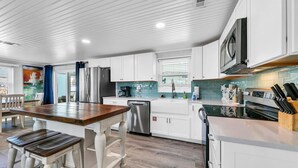 A modern kitchen with white cabinets, stainless steel appliances, and a wooden dining table.