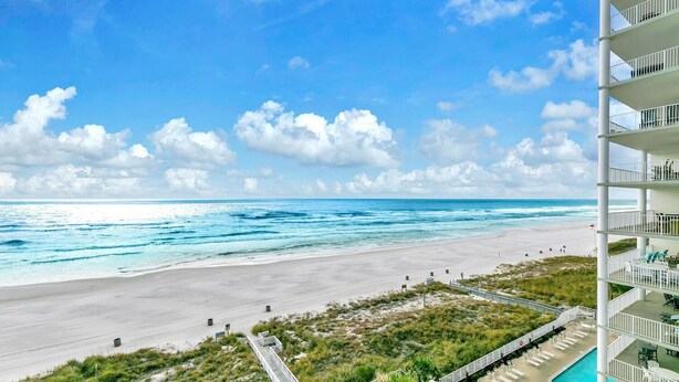 A beachfront hotel with a pool, beach access, and a view of the ocean.