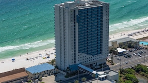 Ein Hochhaus-Hotel mit Blick auf den Strand, mehreren Etagen und einem Parkplatz.