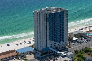 Ein Hochhotel mit Blick auf den Strand, mehreren Etagen und einem Parkplatz.