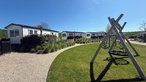 A row of mobile homes with a swing set in the yard. - New chalet 1 on the edge of the Wadden Sea and Amstelmeer with private terrace! (Anna Paulowna)