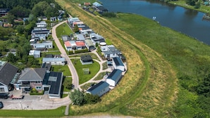 An aerial view of a residential area with houses, a lake, and a road. - New chalet 1 on the edge of the Wadden Sea and Amstelmeer with private terrace! (Anna Paulowna)