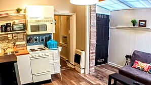 A compact living space with a kitchenette, a dining area, and a seating area with a sofa and a small table. - Charming Jawn in Fabulous Fishtown — W/D, AC, Private Patio & Fast WiFi (Philadelphia)