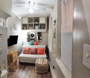 A compact bedroom with a bed, a television, a ceiling fan, and a built-in shelf unit. - Charming Jawn in Fabulous Fishtown — W/D, AC, Private Patio & Fast WiFi (Philadelphia)