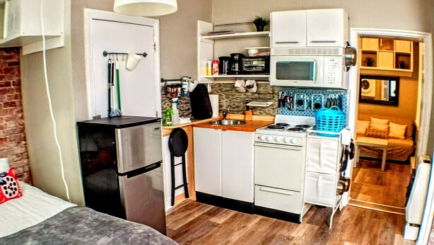 A compact living space with a kitchenette, a bed, and a dining area. - Charming Jawn in Fabulous Fishtown — W/D, AC, Private Patio & Fast WiFi (Philadelphia)