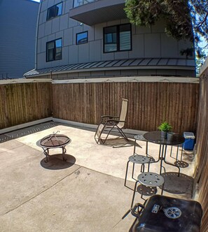 An outdoor patio area with a wooden fence, a rocking chair, and a small table with chairs. - Charming Jawn in Fabulous Fishtown — W/D, AC, Private Patio & Fast WiFi (Philadelphia)