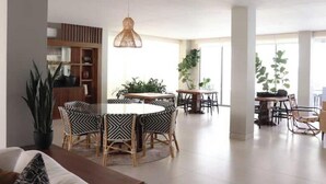 A spacious living area with a round dining table surrounded by patterned chairs, a hanging light fixture, and large windows allowing natural light. - Casa El Encanto Priv Rooftop With Tub Best Loc (El Tezal)