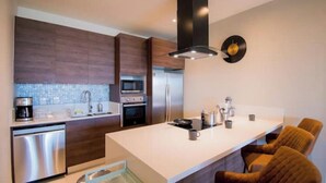 A modern kitchen with a central island, stainless steel appliances, and a microwave. - Casa El Encanto Priv Rooftop With Tub Best Loc (El Tezal)