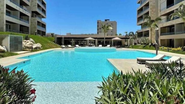 A swimming pool surrounded by modern buildings, with lounge chairs and umbrellas. - Casa El Encanto Priv Rooftop With Tub Best Loc (El Tezal)