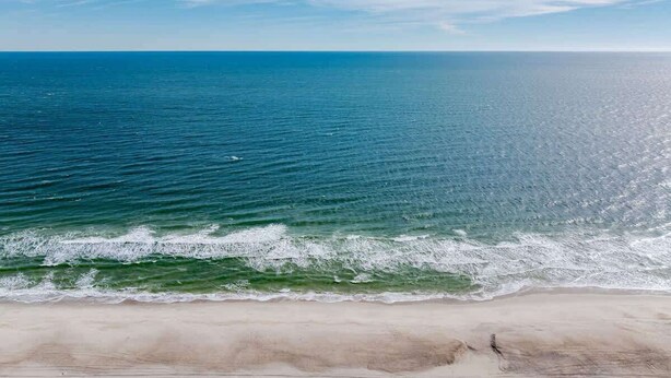 Une plage offrant une vue dégagée sur l’océan et bordée d’un rivage sablonneux.