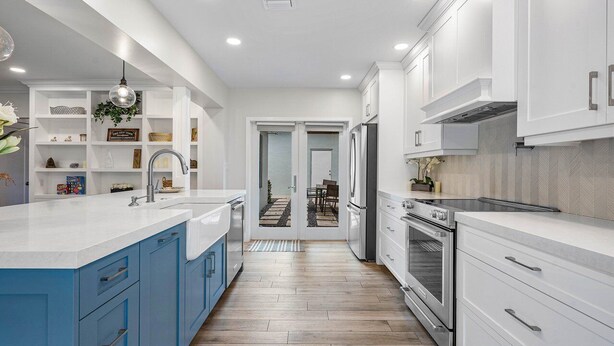 A modern kitchen with white and blue cabinetry, a central island, and a view into the dining area. - Downtown Las Olas Paradise + HOT TUB (Fort Lauderdale)