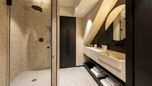 Un baño moderno con cabina de ducha de vidrio, tocador con espejo y un perchero para toallas.