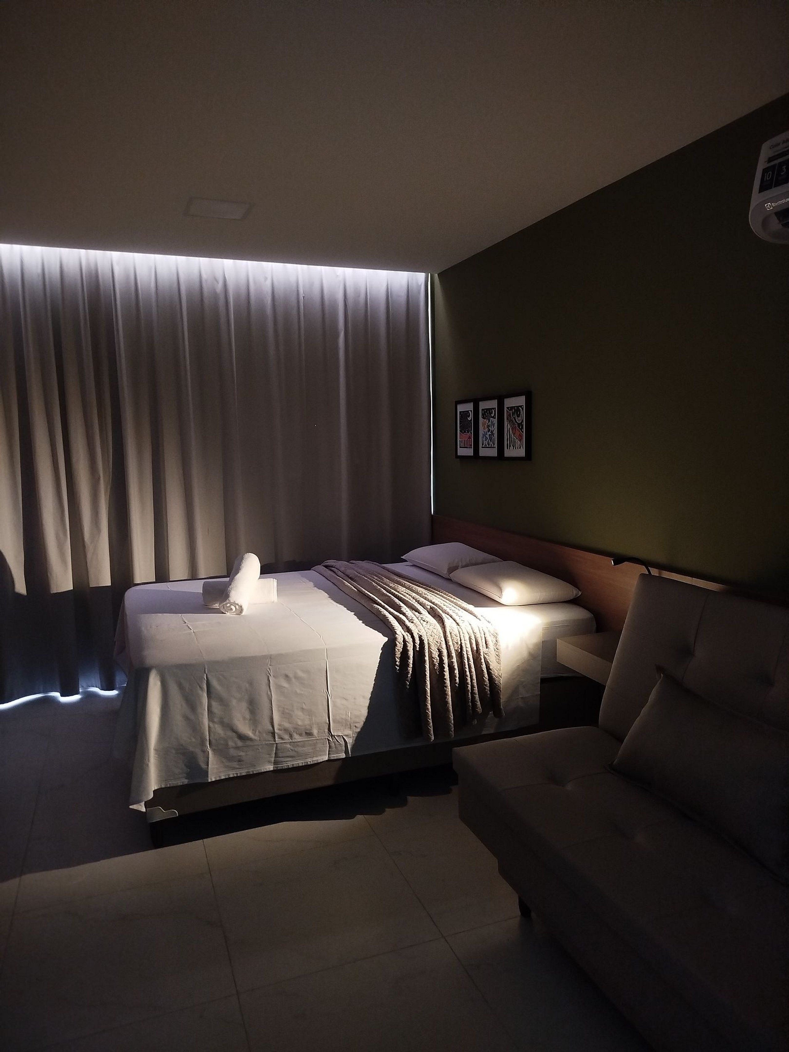 Et hotelværelse med en seng, en sofa og et TV på væggen.