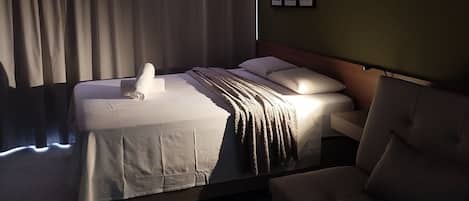 A hotel room with a bed, a sofa, and a wall-mounted TV.