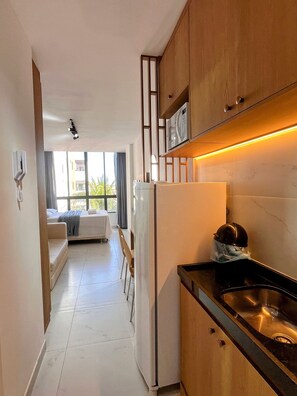 A modern kitchen with wooden cabinets, a stainless steel sink, and a built-in oven. - Porto City - Porto de Galinhas (Ipojuca)