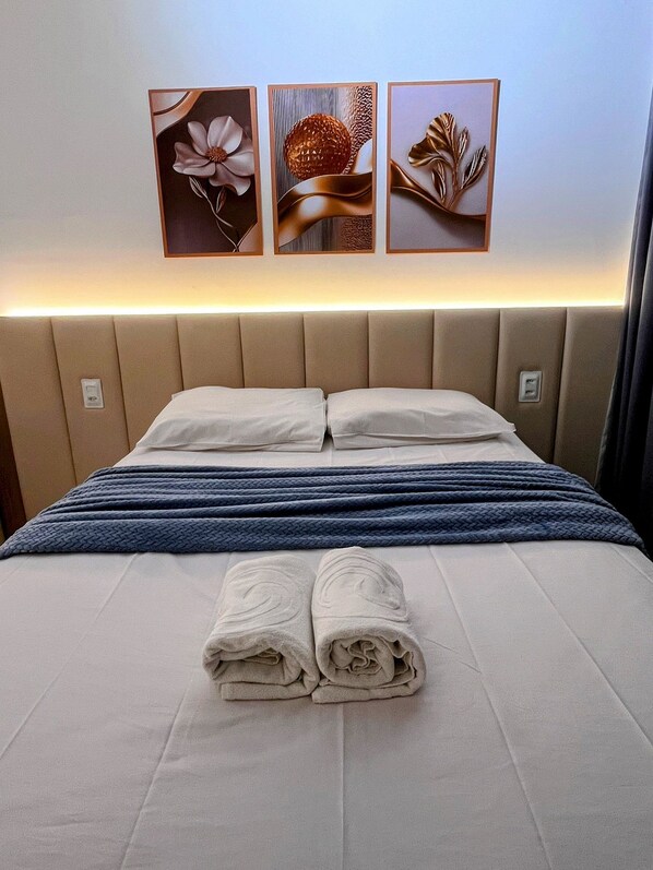 A hotel room with a bed, two pillows, a blue blanket, and three wall art pieces. - Porto City - Porto de Galinhas (Ipojuca)