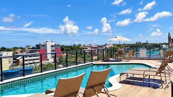 A rooftop pool area with lounge chairs and a view of the cityscape.
