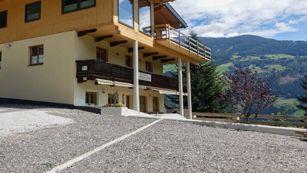 Un immeuble de deux étages doté d’un balcon, de grandes fenêtres et offrant une vue sur un paysage montagneux.