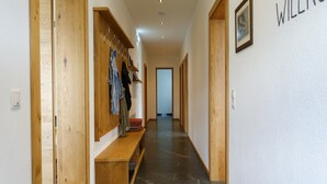 Un couloir avec des portes en bois, un banc et un porte-manteau sur lequel sont suspendus des vêtements.