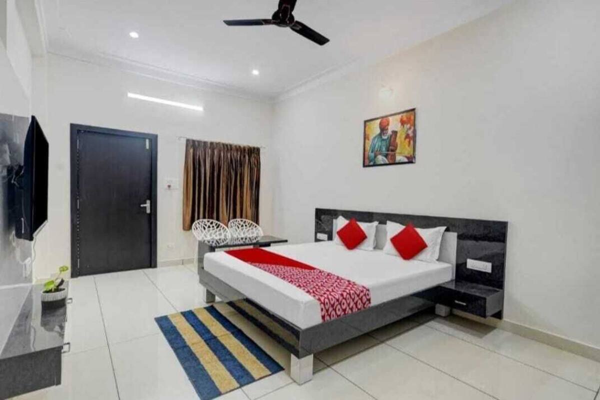 Un dormitorio moderno con cama, mesitas de noche, ventilador de techo, puerta y un cuadro en la pared.