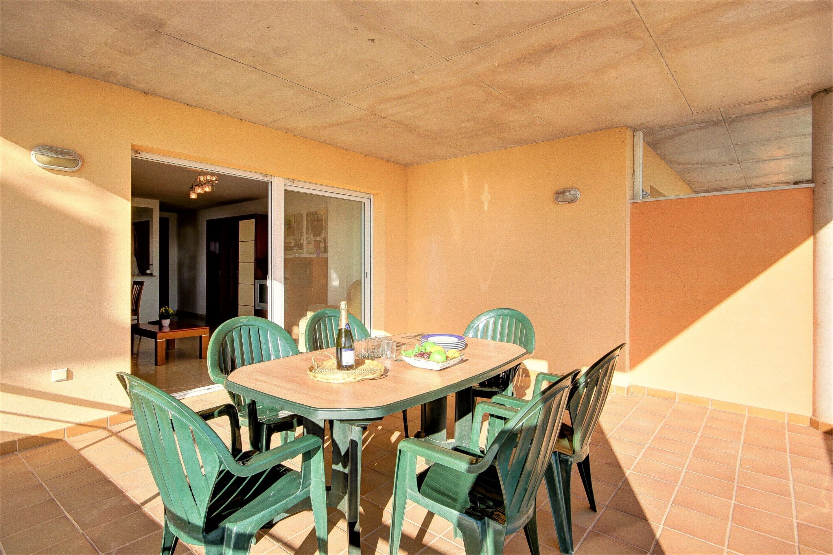 A dining area with a table and chairs, a bottle, and a plate of food.