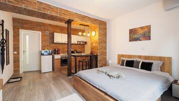 Un dormitorio moderno con una cama de madera, una pequeña kitchenette y una pared de ladrillo.