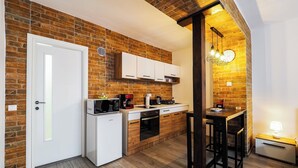 A compact kitchen with a brick wall, white cabinets, a microwave, and a coffee maker. - Ben Apartments (Sibiu)