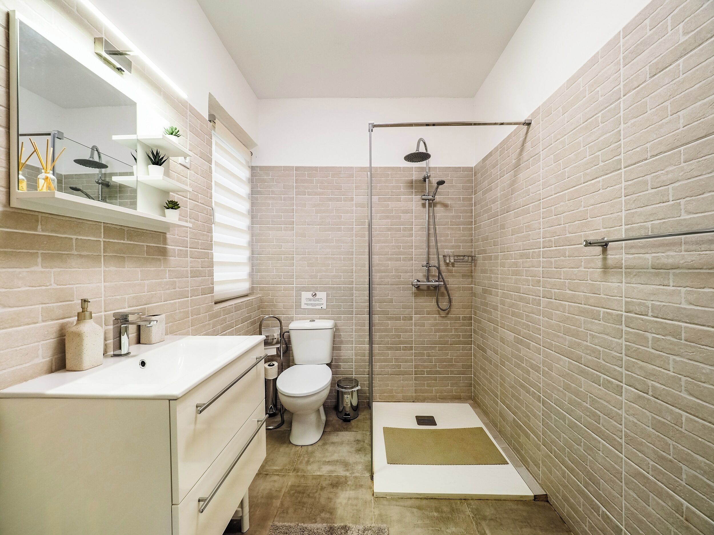 Une salle de bain moderne équipée d’une douche, de toilettes et d’un meuble-lavabo.